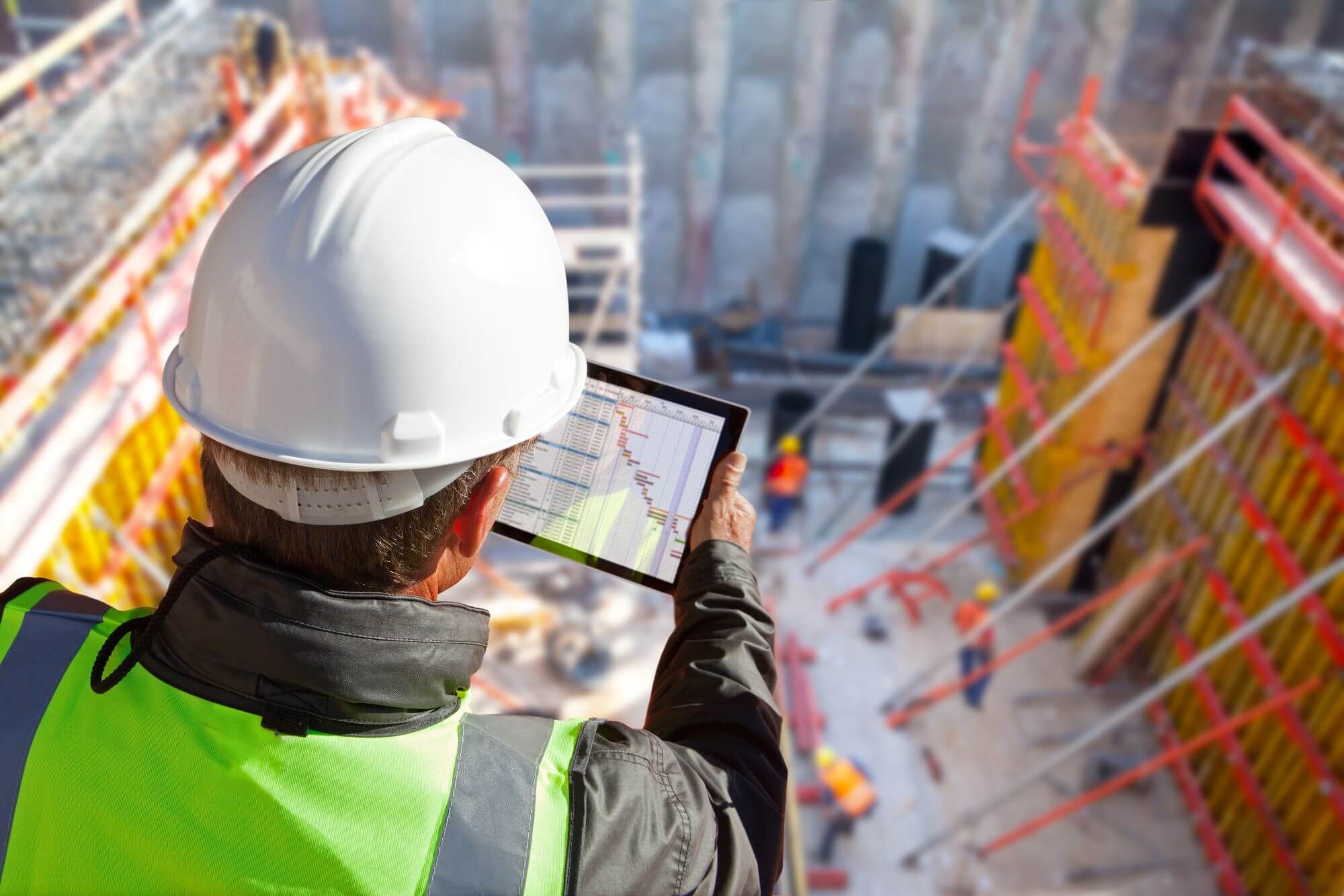 Civil engineer overlooking job site and looking at tablet