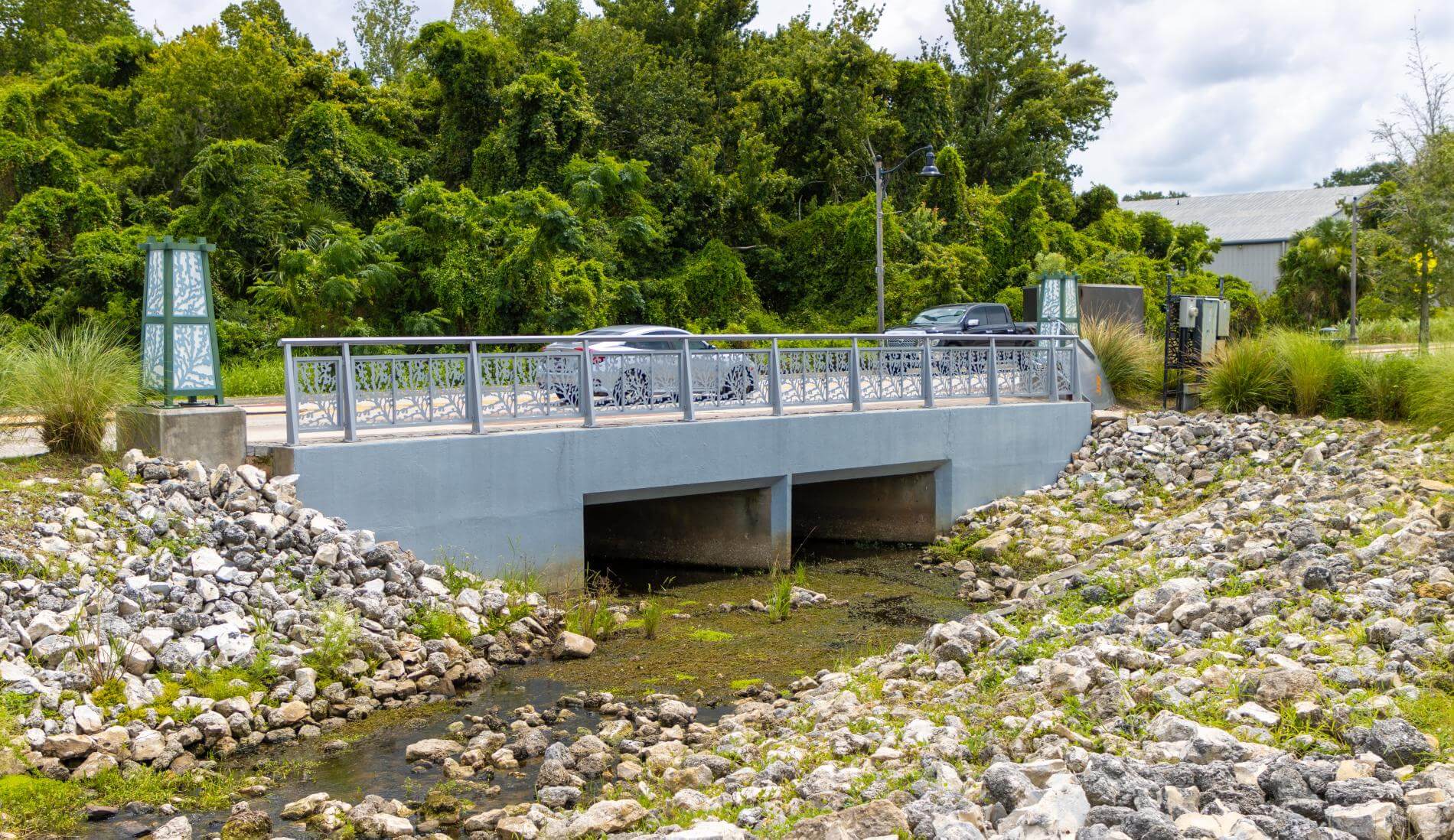 A small concrete bridge over a shallow, rocky stream with trees in the background